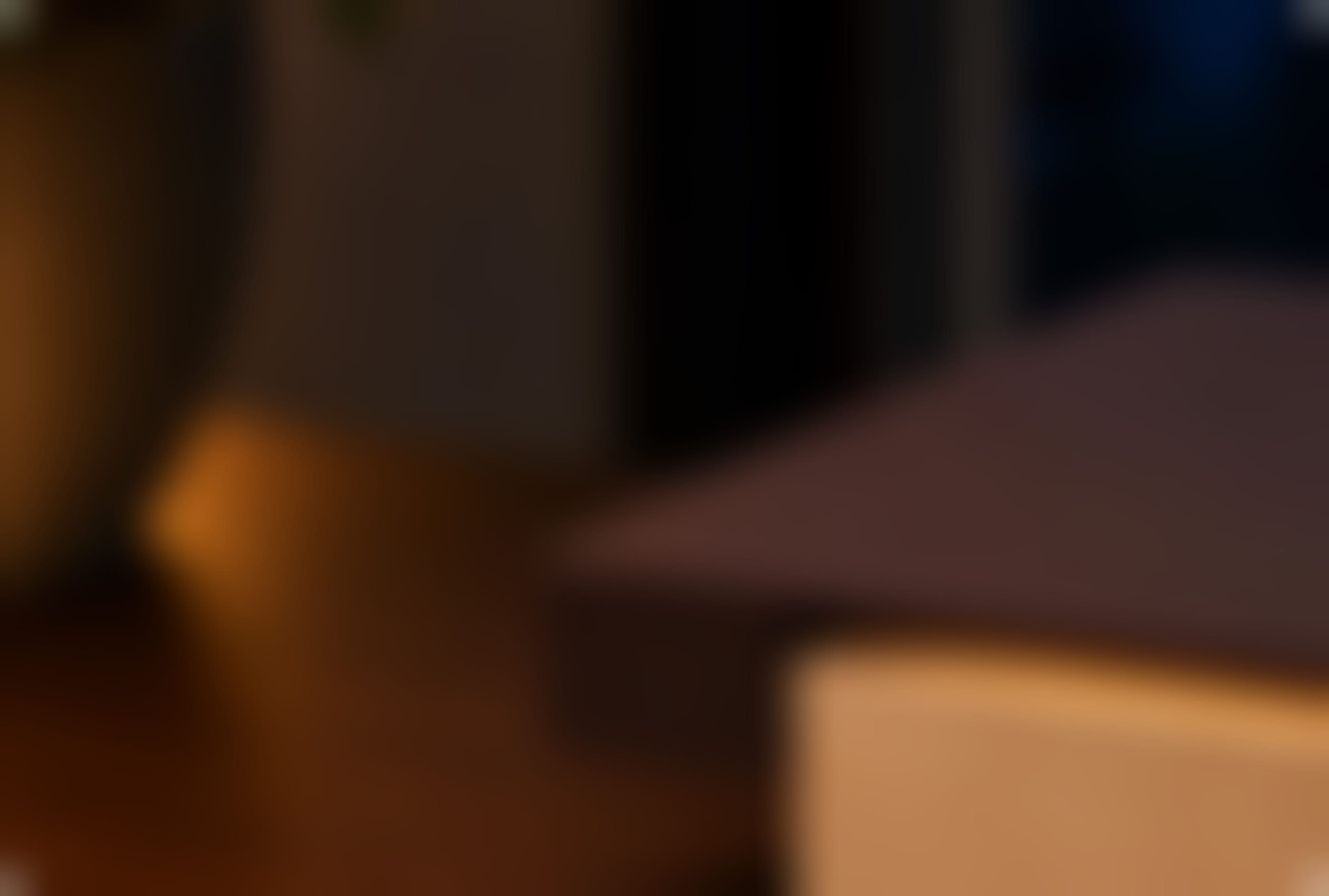 A close-up of the Vora Aegis at dusk: the walnut slab and glowing maple drawer entering from the right, on a wooden sideboard.